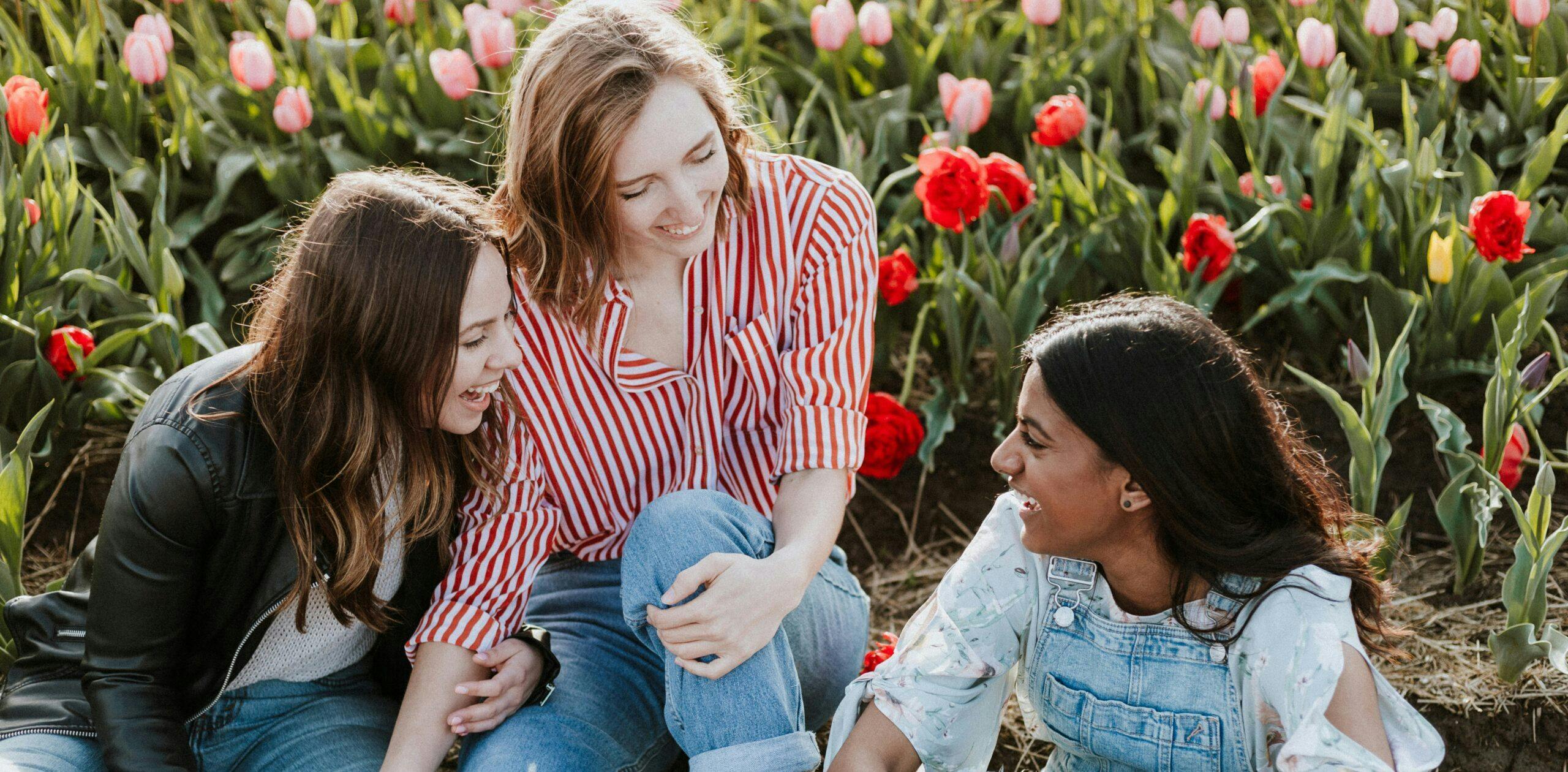 Three young women in a flower field, laughing.